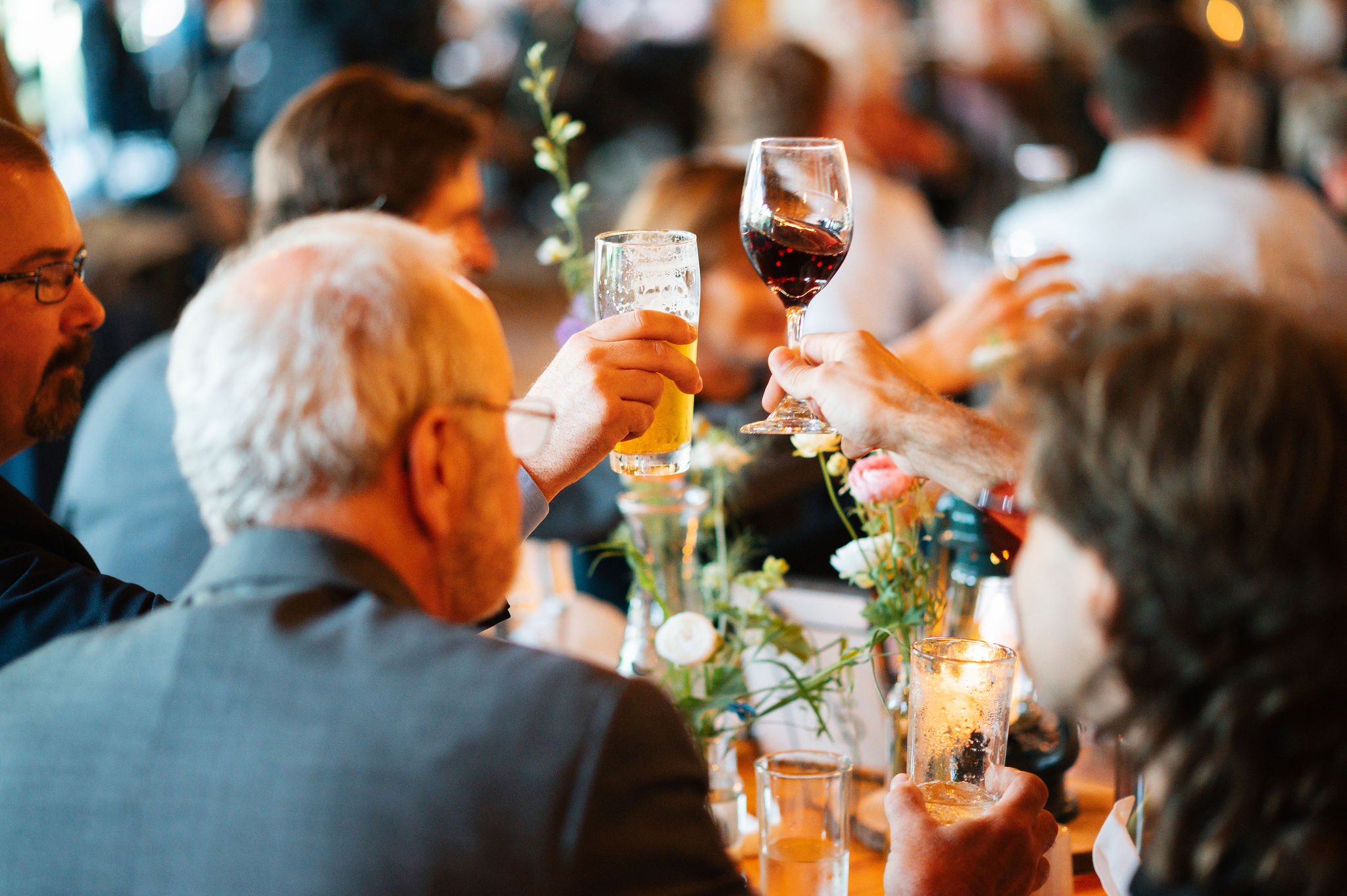 Two people holding their glasses up to cheers each other at wedding.