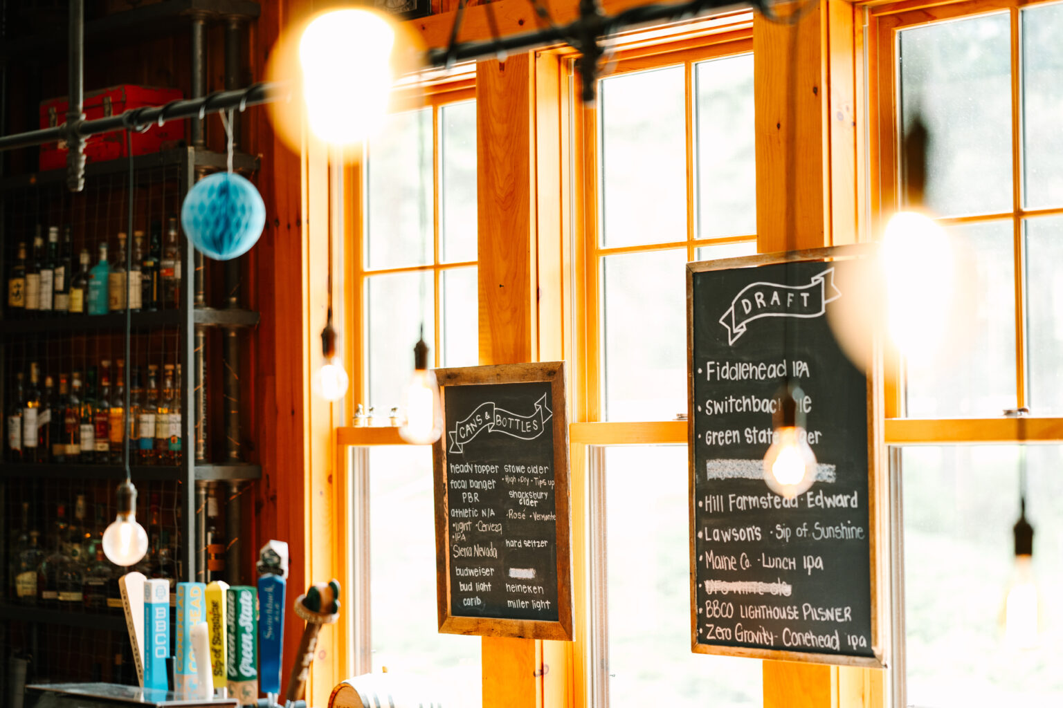 An image of the "draft" and "cans & bottles" black chalkboard signs listing the beer selections behind the bar at the Mad River Barn